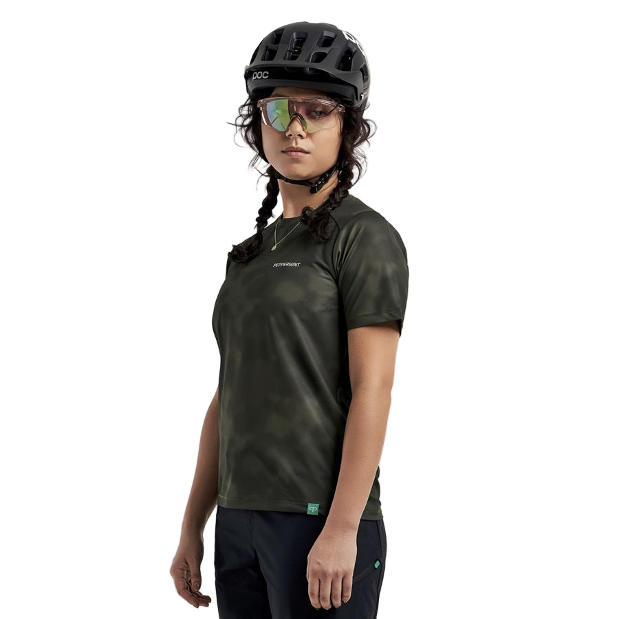 Person wearing a green PeppermintTrail SS cycling jersey and helmet on a white background