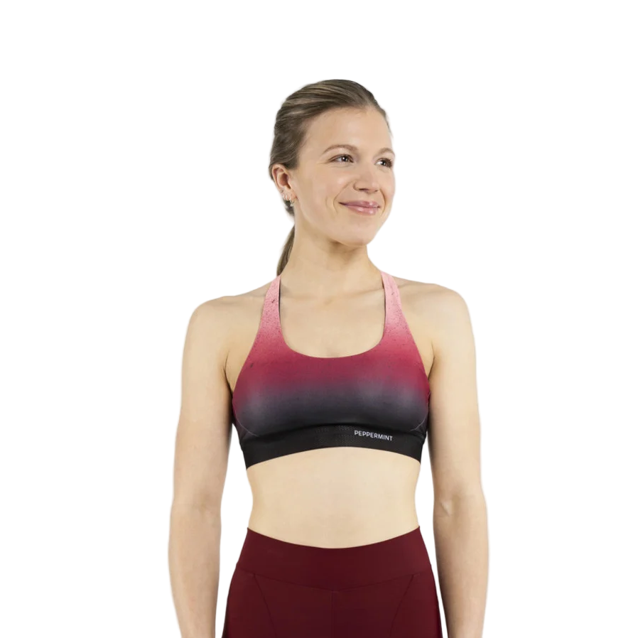Woman wearing a gradient sports bra with maroon and black design on a white background